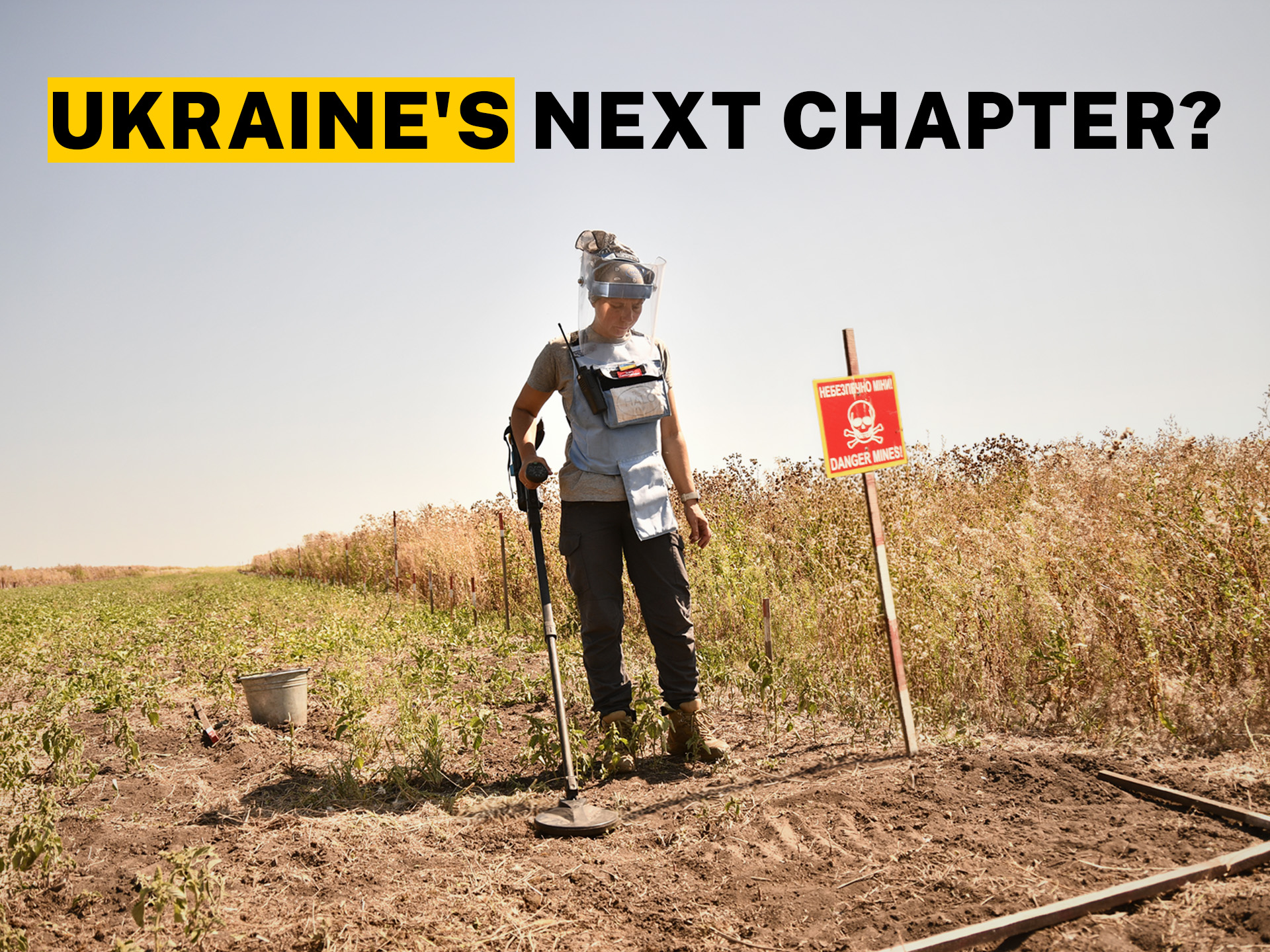 A long shot of a person using a mine detector over a sadny piece of ground next to a field. A heading on the image reads ‘Ukraine‘s next chapter?’