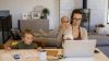 A mother trying to work from home while holding her daughter and watching her son during the COVID-19 home quarantine.